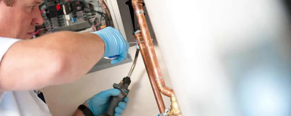 Water heater repair technician testing copper pipe connections and controls in Oak Park, IL